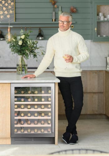 Stainless steel 60cm undercoutner wine cooler in green and wood kitchen with a man drinking wine